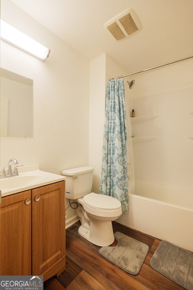 bathroom with toilet, vanity, wood finished floors, and visible vents