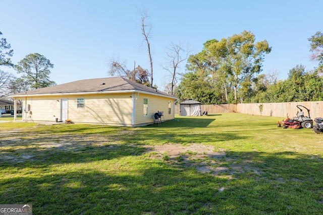 view of yard with fence, an outdoor structure, and a shed