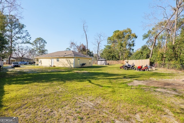 view of yard with fence, an outdoor structure, and a shed