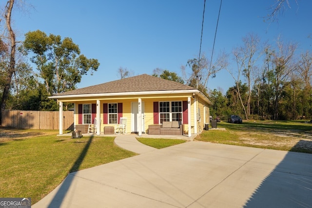 bungalow with covered porch, a shingled roof, fence, and a front yard