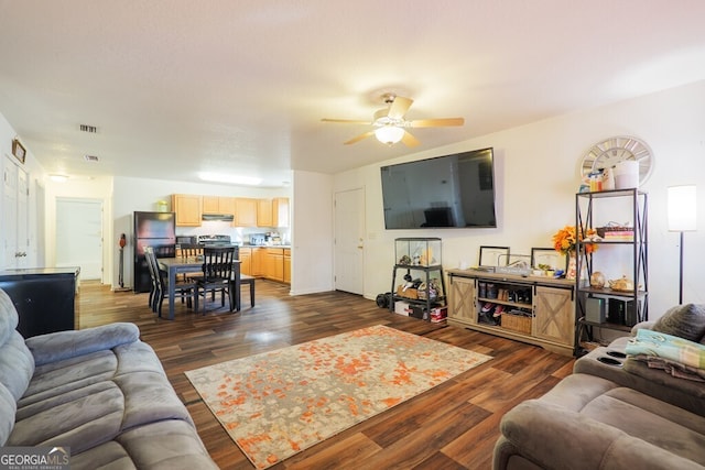 living room with a ceiling fan, visible vents, and dark wood-type flooring