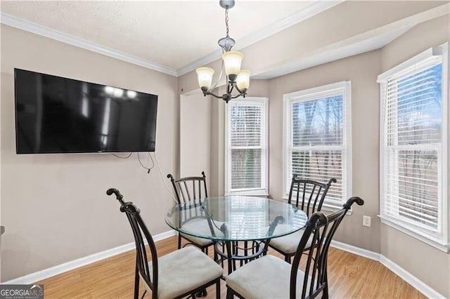 dining area featuring a notable chandelier, crown molding, light wood-type flooring, and baseboards