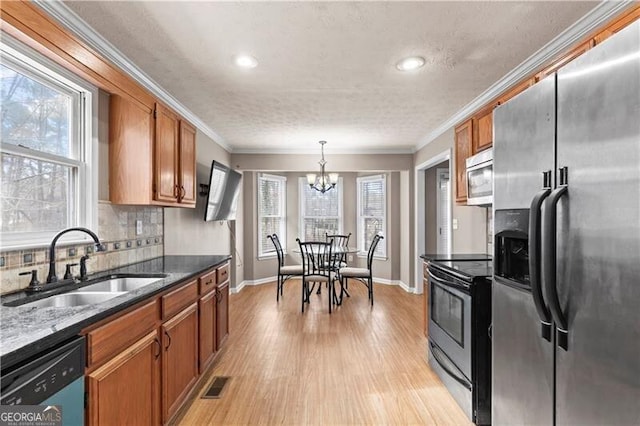 kitchen featuring stainless steel appliances, brown cabinetry, a sink, and tasteful backsplash