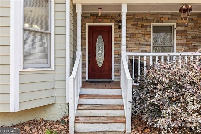 property entrance with covered porch and stone siding