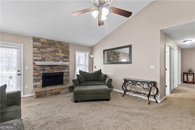 carpeted living room with baseboards, vaulted ceiling, a ceiling fan, and a stone fireplace