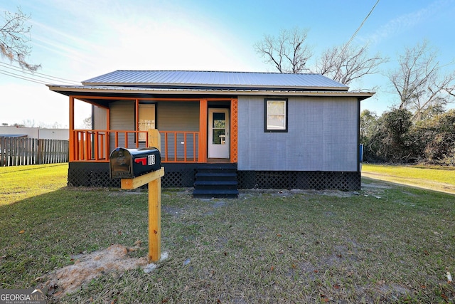 view of front of property featuring metal roof, a front lawn, and fence