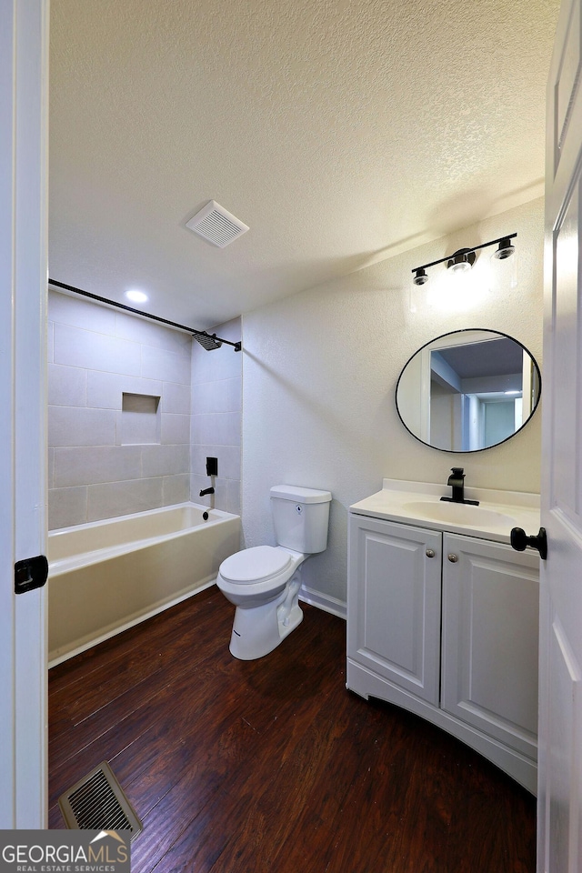 bathroom with visible vents, a textured ceiling, toilet, and wood finished floors