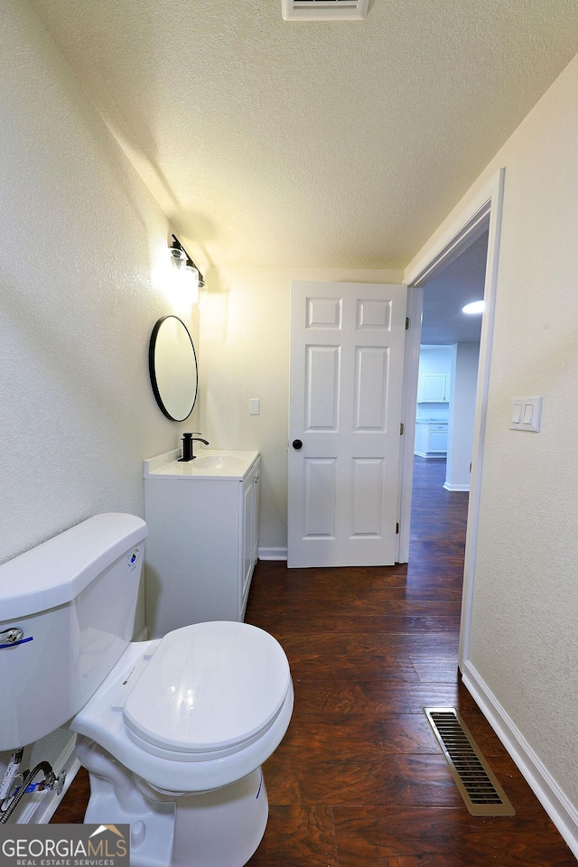 bathroom featuring visible vents, a textured wall, toilet, a textured ceiling, and wood finished floors