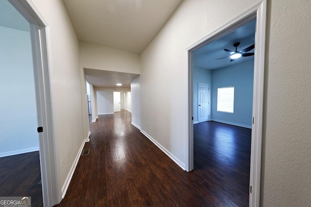 hall featuring wood finished floors, visible vents, and baseboards