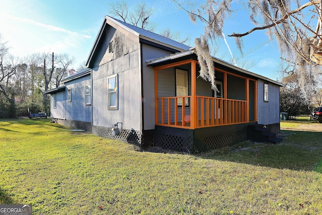 view of side of property with covered porch, metal roof, and a lawn