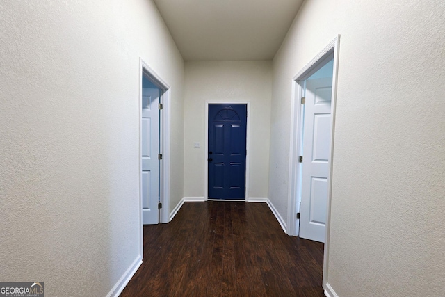 hallway with a textured wall, wood finished floors, and baseboards