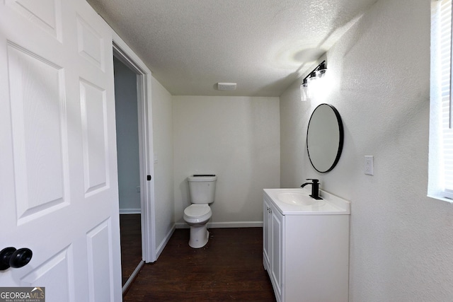 bathroom with baseboards, toilet, wood finished floors, a textured ceiling, and vanity