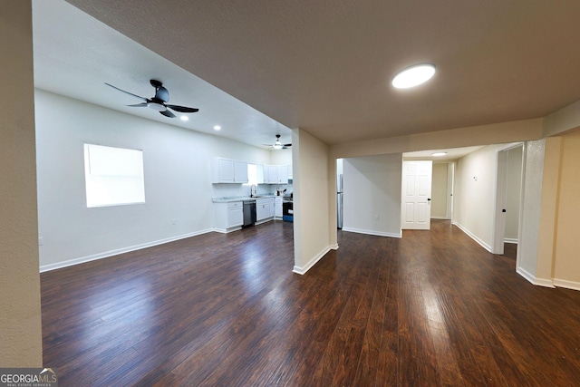 unfurnished living room with a sink, ceiling fan, baseboards, and dark wood-type flooring