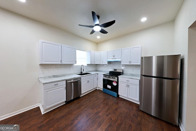 kitchen with appliances with stainless steel finishes, dark wood-type flooring, white cabinets, a sink, and under cabinet range hood