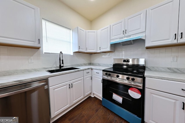 kitchen with dark wood finished floors, stainless steel appliances, white cabinets, a sink, and under cabinet range hood