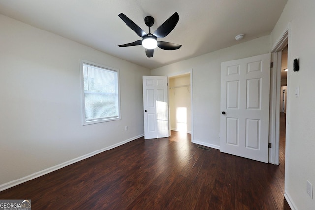 unfurnished bedroom featuring ceiling fan, dark wood-style flooring, visible vents, and baseboards