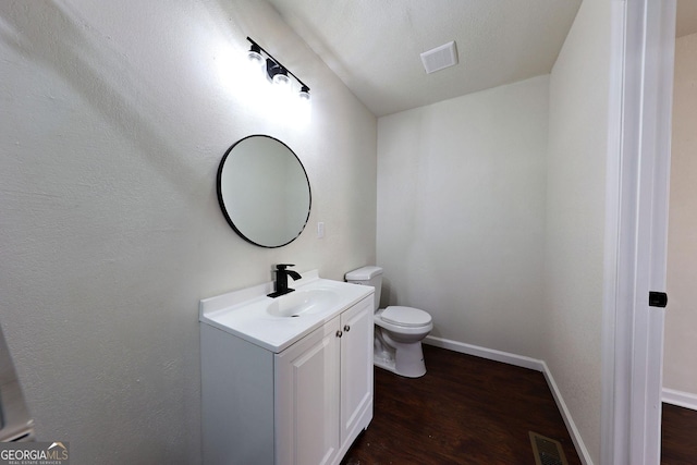 bathroom featuring toilet, visible vents, wood finished floors, and vanity