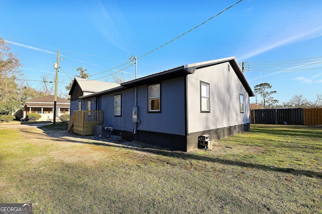 view of side of home with central AC unit, a lawn, metal roof, crawl space, and fence