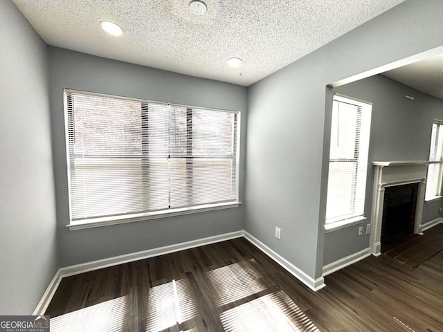 unfurnished dining area featuring a healthy amount of sunlight, a fireplace, wood finished floors, and baseboards