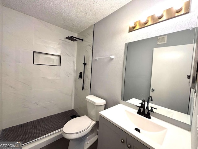 full bathroom featuring visible vents, tiled shower, toilet, a textured ceiling, and vanity