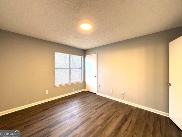 unfurnished bedroom featuring dark wood finished floors, a textured ceiling, and baseboards