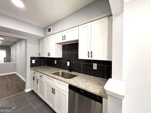 kitchen featuring decorative backsplash, a textured ceiling, stainless steel dishwasher, white cabinetry, and a sink