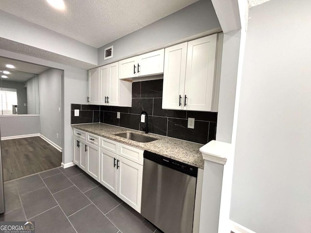 kitchen with tasteful backsplash, visible vents, stainless steel dishwasher, white cabinetry, and a sink