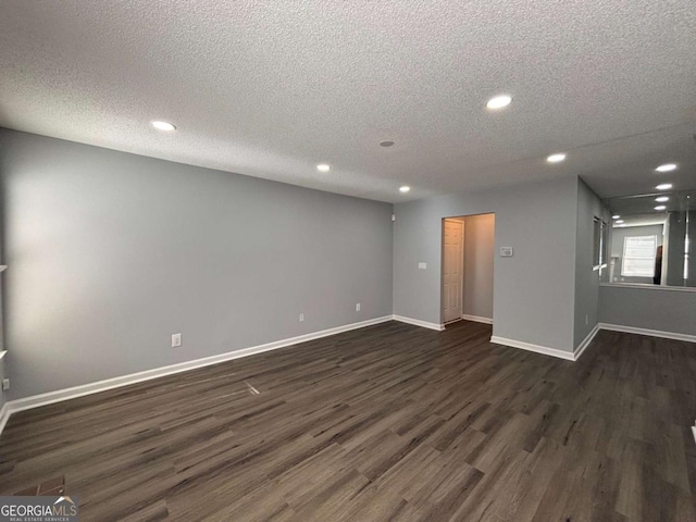 unfurnished room with a textured ceiling, baseboards, dark wood-type flooring, and recessed lighting