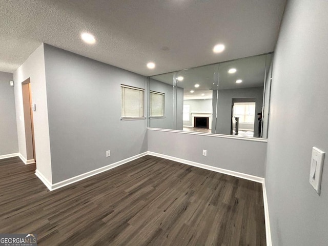 unfurnished room with dark wood-style floors, a textured ceiling, and baseboards