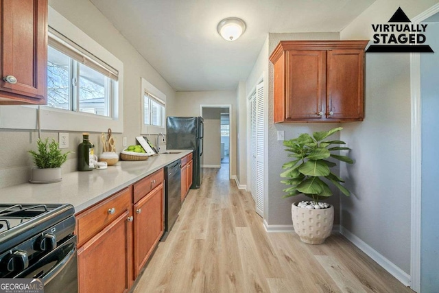 kitchen with black appliances, a sink, light countertops, and light wood-style floors