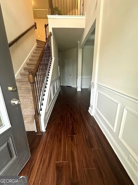 hallway featuring a decorative wall, wainscoting, stairs, and wood finished floors