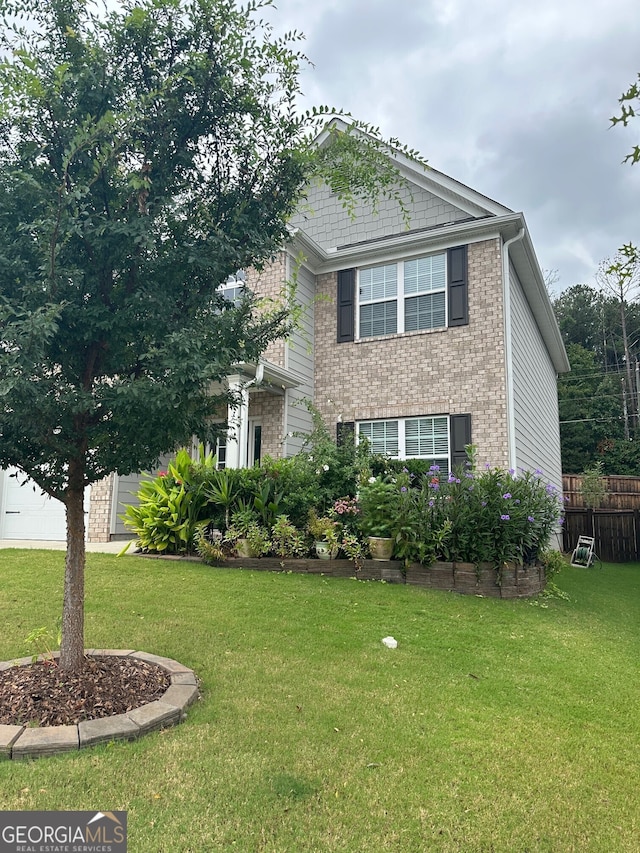 view of front of house featuring a front yard, a garage, fence, and brick siding