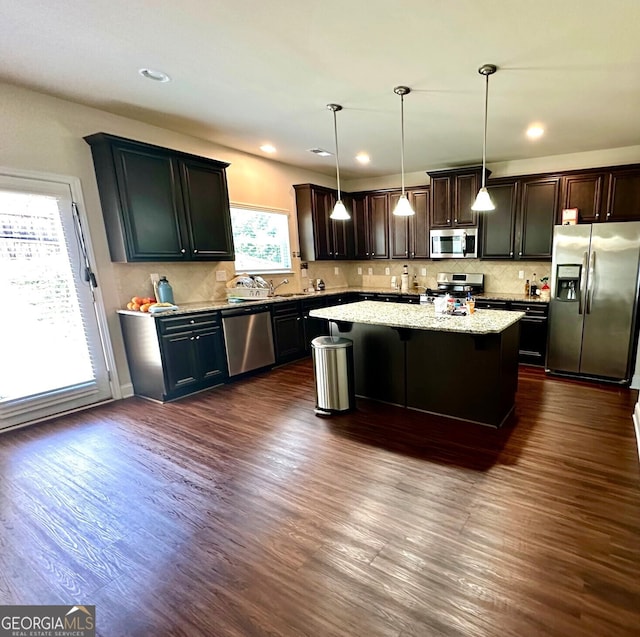 kitchen featuring a kitchen island, backsplash, stainless steel appliances, and dark wood-type flooring