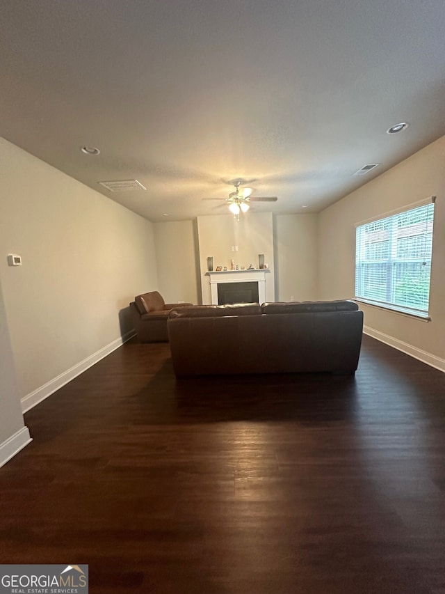 unfurnished living room featuring dark wood finished floors, visible vents, a fireplace, and baseboards