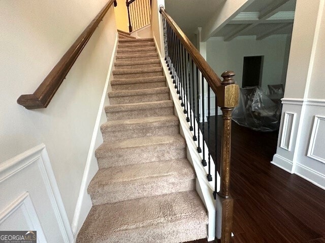 stairway featuring a decorative wall, wainscoting, and wood finished floors