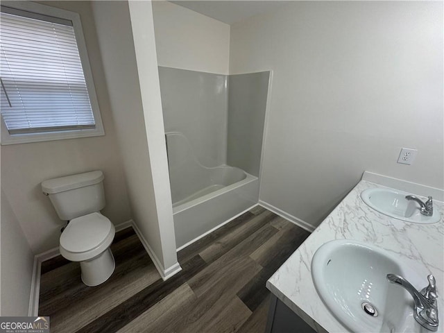 full bath featuring double vanity, wood finished floors, a sink, and toilet