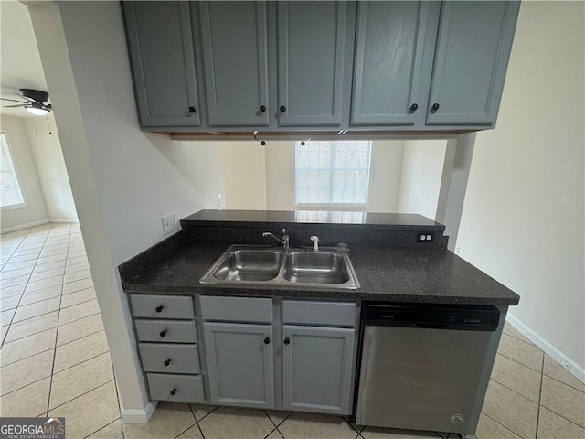 kitchen with a sink, dark countertops, stainless steel dishwasher, and light tile patterned flooring