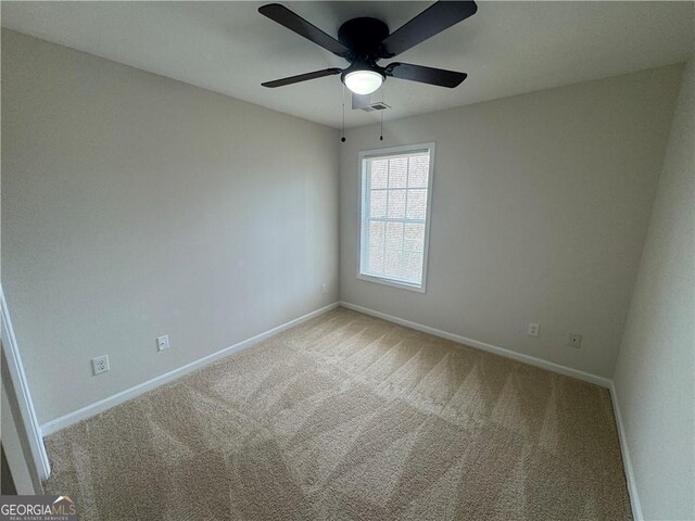 empty room with a ceiling fan, carpet flooring, visible vents, and baseboards