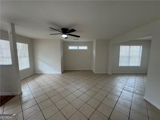 empty room with ceiling fan, baseboards, and light tile patterned floors