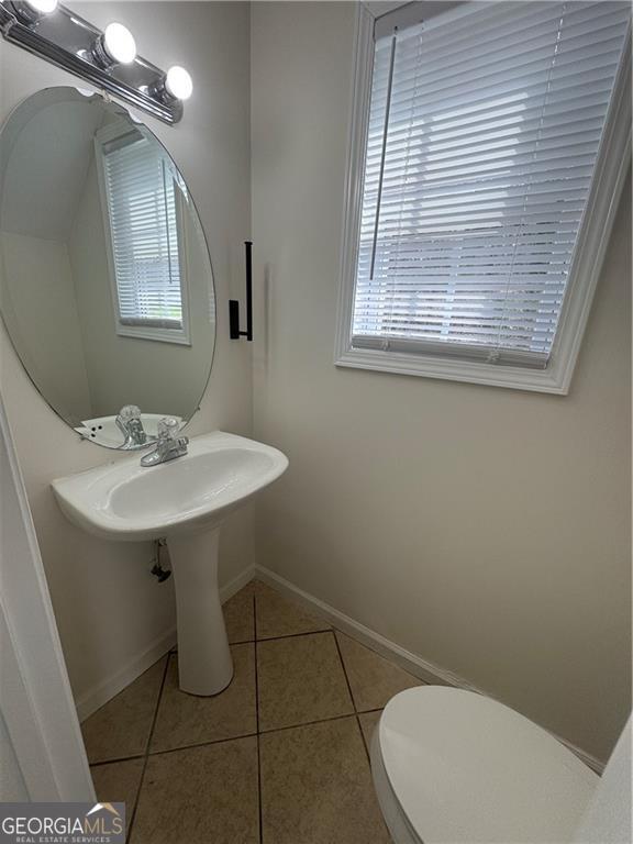 bathroom with tile patterned flooring, toilet, and baseboards