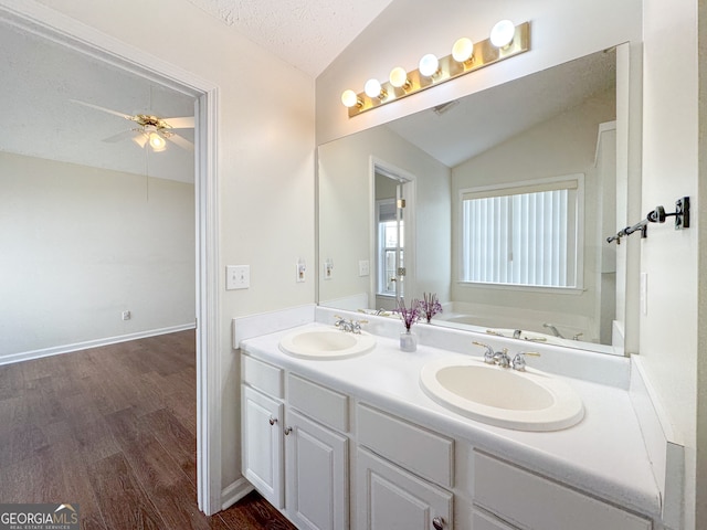 full bath featuring vaulted ceiling, wood finished floors, a textured ceiling, and a sink