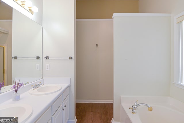 bathroom featuring double vanity, a garden tub, a sink, and wood finished floors