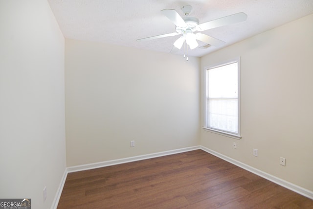 empty room featuring dark wood-style floors, ceiling fan, a textured ceiling, and baseboards