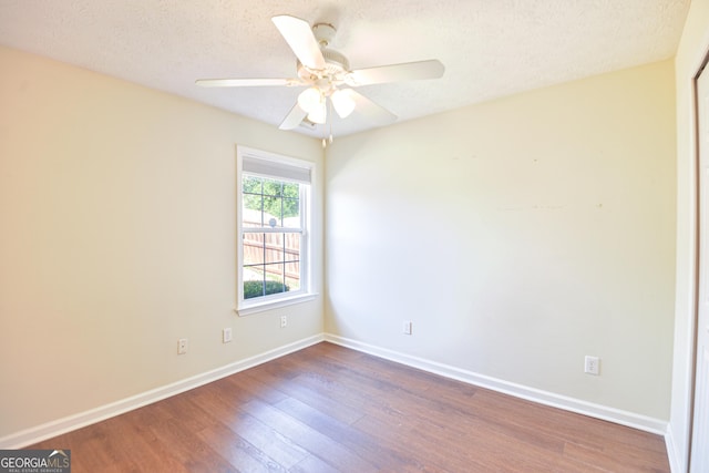 empty room with ceiling fan, a textured ceiling, baseboards, and wood finished floors