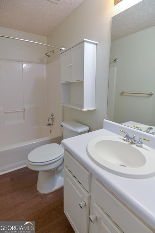 full bath with bathing tub / shower combination, toilet, a textured ceiling, vanity, and wood finished floors