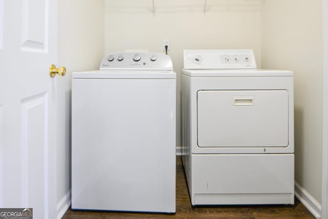 clothes washing area with laundry area, dark wood-type flooring, washer and clothes dryer, and baseboards