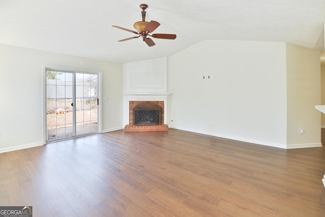 unfurnished living room with ceiling fan, baseboards, vaulted ceiling, a brick fireplace, and dark wood-style floors