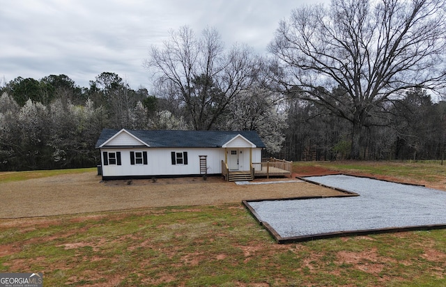 view of front of home featuring a wooden deck, a wooded view, and a front yard