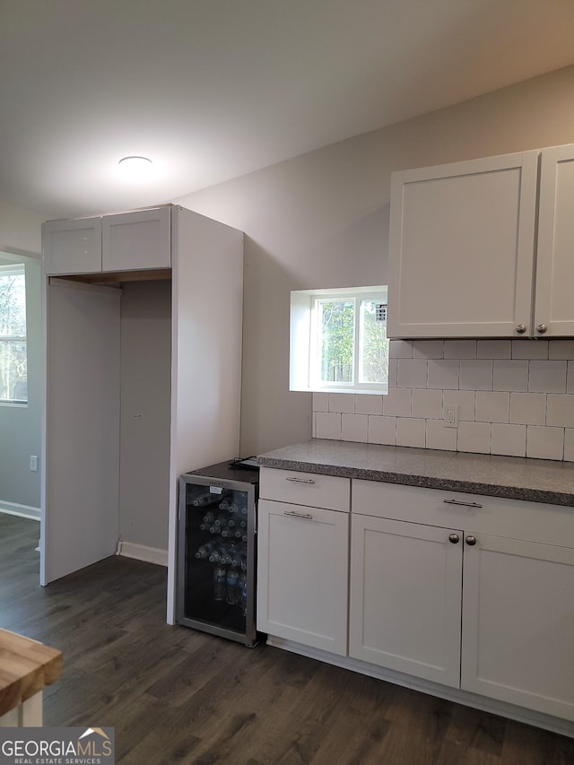 kitchen with wine cooler, dark wood-type flooring, white cabinets, decorative backsplash, and dark countertops