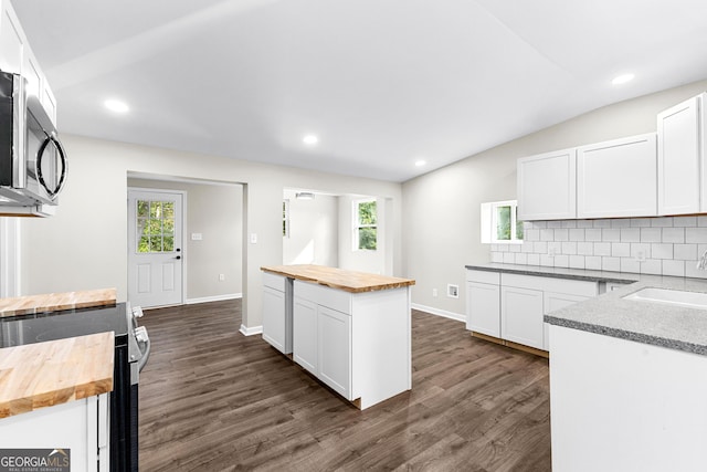 kitchen featuring vaulted ceiling, butcher block counters, a sink, and tasteful backsplash